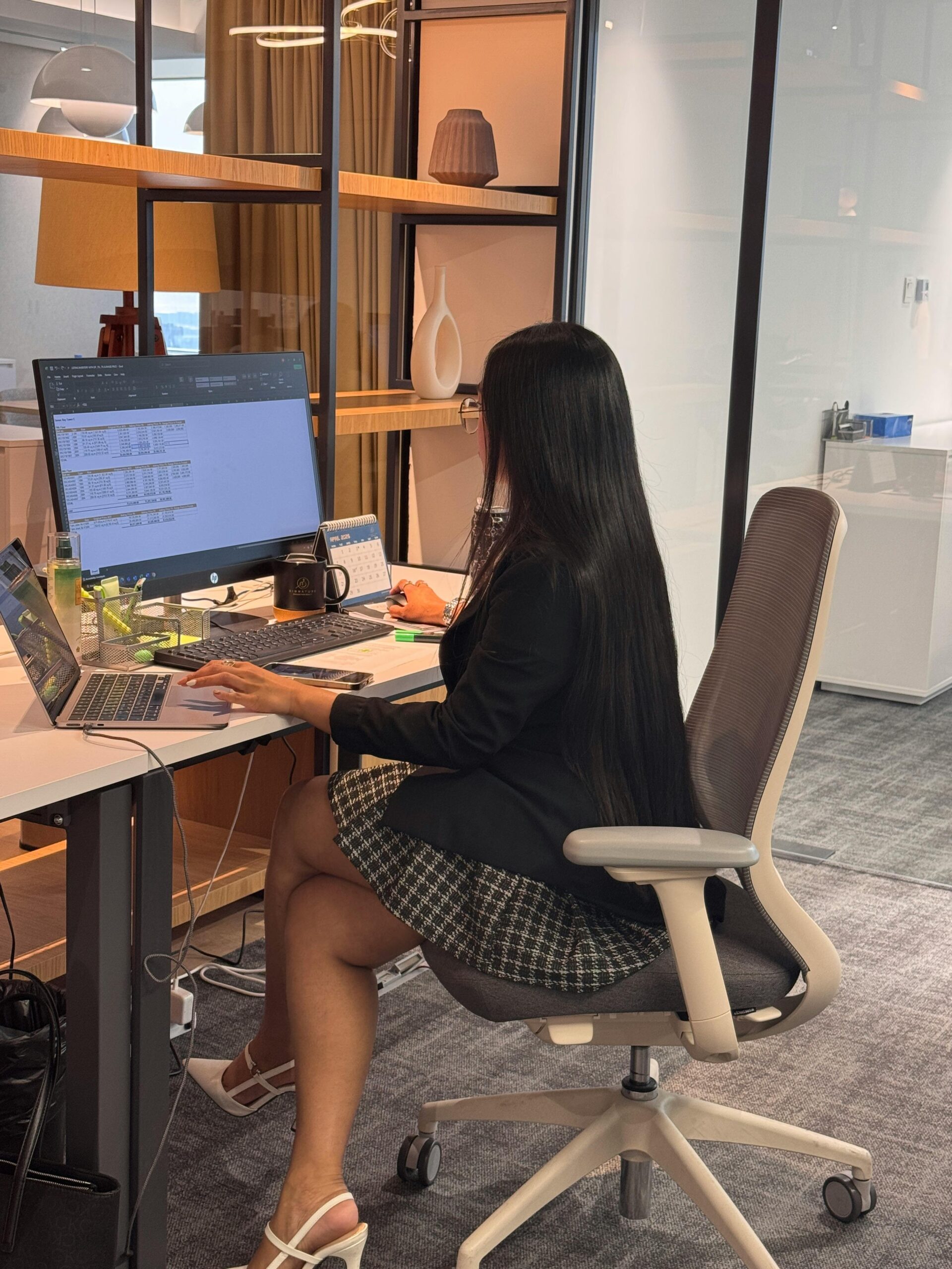 Businesswoman working at a desk in a modern office setting. Collaborative workspace environment.